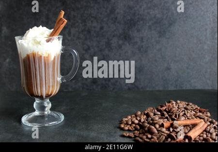 Schaumig Kaffee trinken. Cappuccino oder Latte in einem transparenten Glas auf dunklem Grund Stockfoto