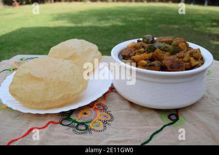 Indisches gujarati Mittagessen oder Abendessen von puri und Undhiyu oder Undhiya Curry und gerollte Papad für Festival Saison von makar sankranti für januar. Außenbereiche Stockfoto