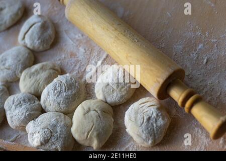 Teig zum Backen vorbereiten, Hefeteig ausrollen, Rohlinge für Torten und ein Nudelholz sind auf einem Holzbrett Stockfoto