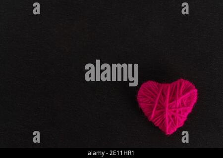 Herz aus rosa Faden auf schwarzem Hintergrund. Konzept zum Valentinstag. Hohe Qualität Stockfoto