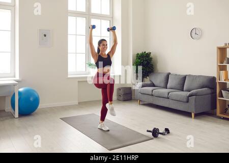 Happy fit Frau in Sportswear macht Übungen mit Hanteln während Workout zu Hause Stockfoto