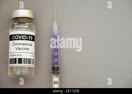 Konzept. Coronavirus-Impfstoff und Spritze auf grauem Hintergrund. Hohe Qualität Stockfoto