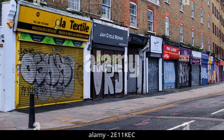 Graffiti bedeckte Schaufensterläden und geschlossene Geschäfte, Wentworth Street, Petticoat Lane Market, London, Sonntag, 3. Januar 2021 Stockfoto