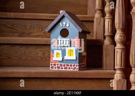 Auf der Holztreppe eines Hauses steht eine handbemalte, lebendige Vogelhaus-Nahaufnahme. Die Pflege der Vögel, die Natur. Zimmerei arbeiten. Stockfoto