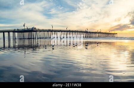 Pismo Beach, California/USA - 1. Januar 2021 Historischer Pismo Beach Pier aus Holz bei Sonnenuntergang, Panoramablick. Ein kultiger kalifornischer Holzsteg im HE Stockfoto