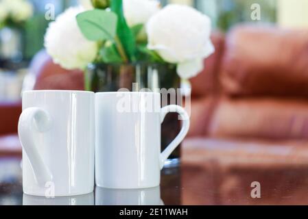 Zwei Tassen Tee oder Kaffee zusammen auf einem Kaffee Tisch in einem hellen Innenraum Stockfoto