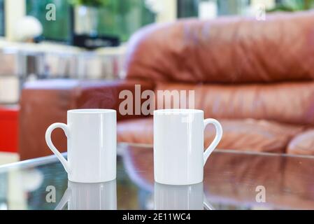 Zwei Tassen Tee oder Kaffee zusammen auf einem Kaffee Tisch in einem hellen Innenraum Stockfoto