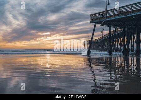 Pismo Beach, California/USA - 1. Januar 2021 Pismo Beach Sonnenuntergang. Hölzerner Pier, eine berühmte Touristenattraktion, breiter Sandstrand, Pazifischer Ozean und Be Stockfoto