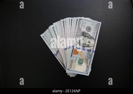 Set von 100 US-Dollar Scheine auf schwarzem Leder Hintergrund. Viele amerikanische Banknoten Stockfoto