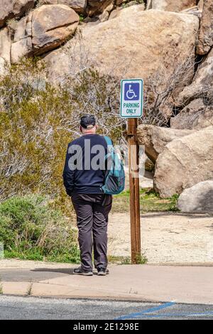 Mann und Behinderte Parken nur Schild entlang der Straße in Joshua Baum Kalifornien Stockfoto