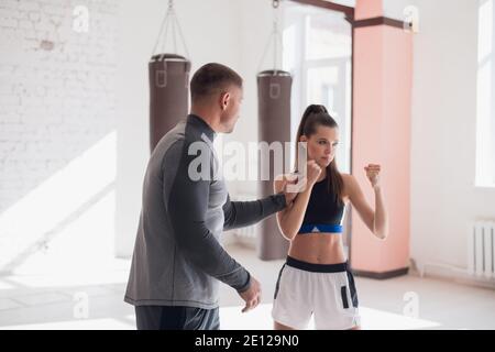 Ein erfahrener Trainer setzt die Technik der Schläge auf ein Junges Mädchen in der Boxhalle Stockfoto