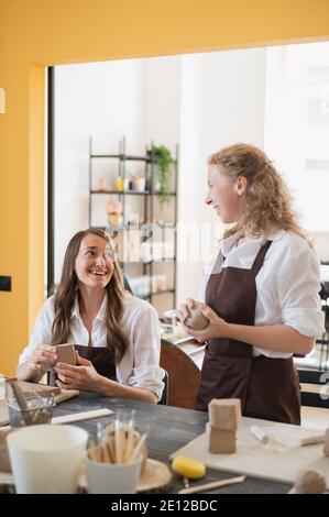 Töpferinnen während des Arbeitsprozesses in der Tonwerkstatt. Frau Meister bereiten Keramik-und Ton-Produkte an großen Holztisch Stockfoto