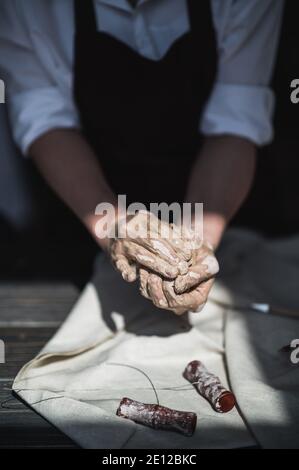 Die Hände der Töpferin Formen eine Tasse aus Ton. Der Prozess der Herstellung von Keramik. Der Keramikmeister arbeitet in seinem Atelier. Nahaufnahme, nur Hände Stockfoto
