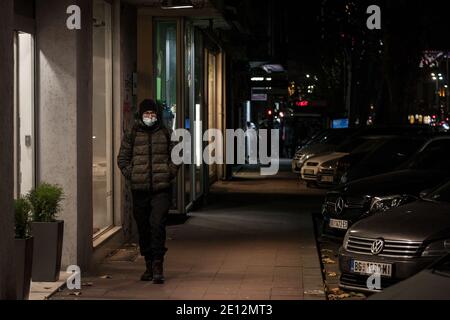 BELGRAD, SERBIEN - 2. DEZEMBER 2020: Junger Mann mit weißem Kaukasier, der eine Atemmaske trägt und nachts allein in den Straßen von Belgrad geht Stockfoto