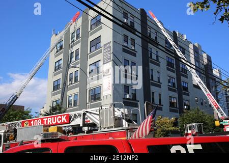 Feuerwehrleute retten Menschen in hochmodernen Gebäude durch erweiterte Leiter Kran von Feuerwehrwagen, Feuerbohrmaschine zu entkommen Stockfoto