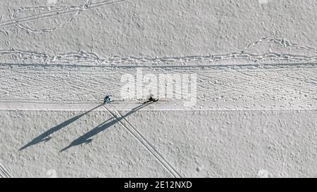 Skipaar direkt von oben gefilmt von einer Drohne auf einer Winterbahn, weiß verschneite Sportfoto aus Vogelperspektive. Stockfoto