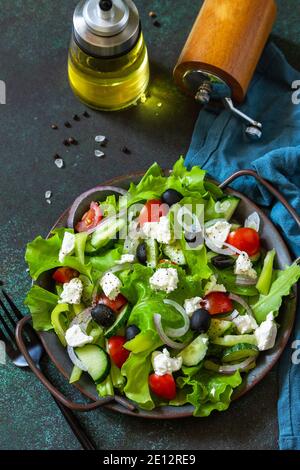 Gesunde Ernährung Lebensmittel. Griechischer Salat aus Feta, frischer Gurke, Tomaten, Paprika, Salat, roter Zwiebel und Oliven mit Olivenöl. Stockfoto