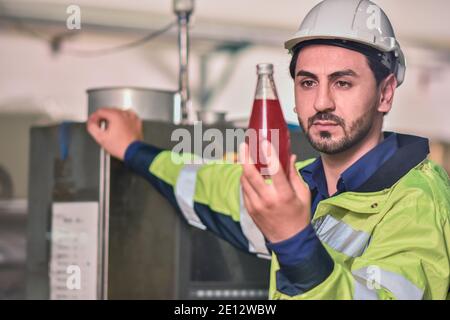 Arbeiter-Ingenieur, der das Getränk in der Maschine auf den Prozess in der Fabrik überprüft Stockfoto