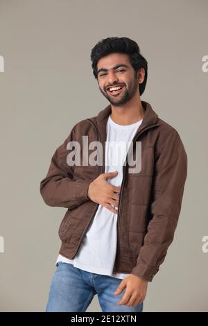 EIN JUNGER MANN, DER DIE KAMERA ANSCHAUT UND LACHT Stockfoto