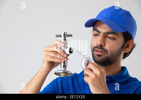 EIN KLEMPNER, DER EIN ROHR ANSIEHT UND ES REPARIERT Stockfoto