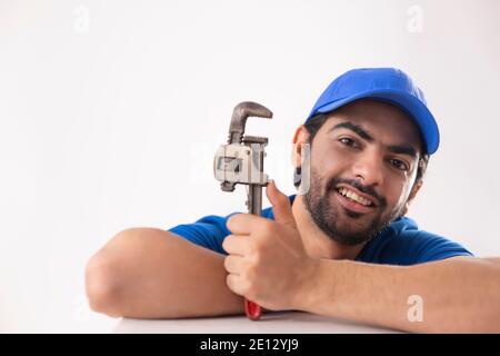 EIN JUNGER KLEMPNER POSIERT GLÜCKLICH MIT SEINER AUSRÜSTUNG Stockfoto