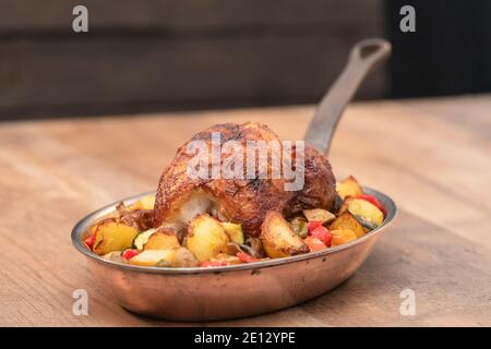 Köstliches Spieß-gebratenes Huhn mit Gemüse auf einer Pfanne auf einem Holztisch. Stockfoto