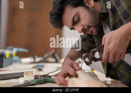 EIN ZIMMERMANN MIT PLYER, UM NAGEL AUS HOLZ ABZUZIEHEN Stockfoto
