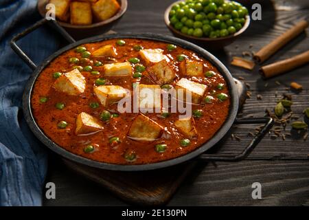 Mattar Paneer oder Hüttenkäse mit Erbsen. Eine vegetarische indische Delikatesse, mit rohen Erbsen und gebratenem Paneer (Hüttenkäse) im Hintergrund. Stockfoto