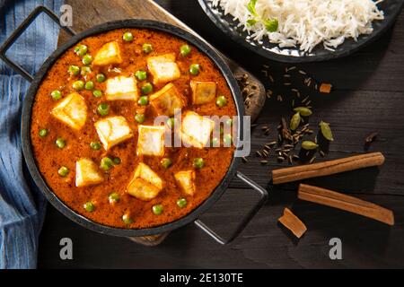 Mattar Paneer oder Hüttenkäse mit Erbsen mit gekochtem/gedünstetem Reis im Hintergrund Stockfoto