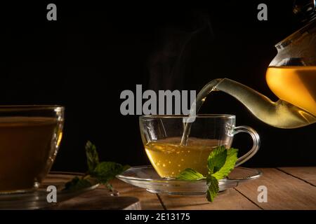 Nahaufnahme von grünem Tee, der aus der Teekanne in gegossen wird becher Stockfoto