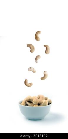 Cashew Gießen in weiße Schüssel vor weißem Hintergrund. Konzept der fliegenden Nahrung. Das Bild enthält den Kopierbereich Stockfoto