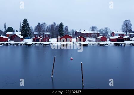 Obbola, Norrland Schweden - 7. Dezember 2020: Kleine Bootslager und Angelhütten am Hafen Stockfoto