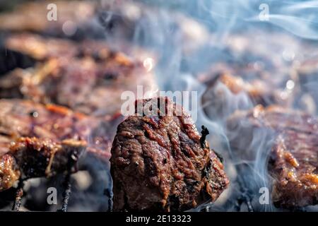 Fleisch auf Spieße gegrillt über einem offenen Feuer mit Rauch aus nächster Nähe. Grill Stockfoto