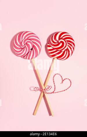 Zwei gebundene Lollipop Candys und rotes Herz am Valentinstag, Liebeskonzept. Stockfoto