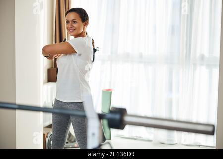 Fröhliche Athletin, die sich zu Hause aufwärmt Stockfoto