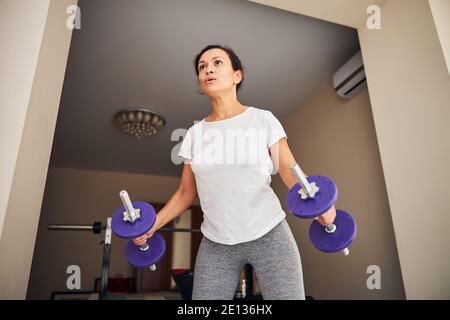 Starke junge Frau, die mit Handgewichten trainiert Stockfoto