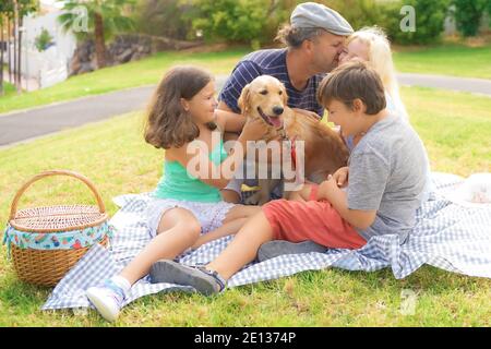 Glückliche Familie macht ein Picknick. Eltern, Kinder und Hund haben Spaß im Urlaub. Reise, Haustier, Urlaub und Liebeskonzept. Stockfoto