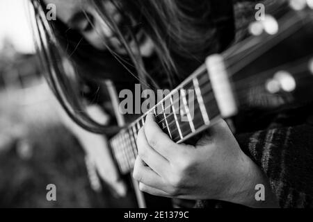 Nahaufnahme Finger auf den Saiten, Mädchen spielt akustische Gitarre. Schwarzweiß-Foto. Stockfoto