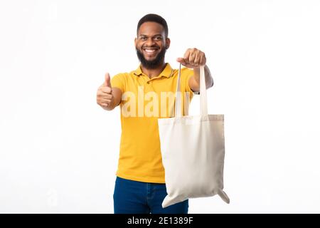 African Man Zeigt Eco Bag Gestikulierenden Daumen-Up Auf Weißem Hintergrund Stockfoto