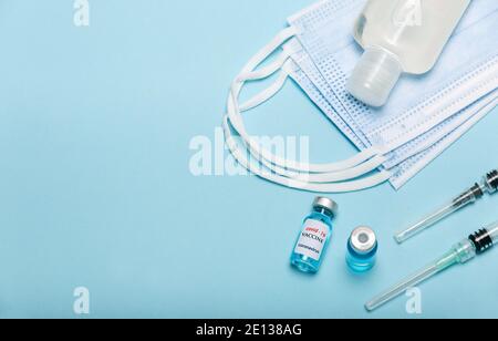 Medizinische Flasche, Händedesinfektionsmittel, Fläschchen, Spritzen und Gesichtsmaske auf blauem Hintergrund mit Kopierraum. Impfungen und Verbesserung der Immunität. Stockfoto