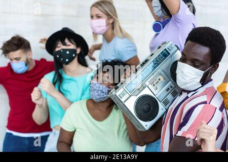 Multirassische Freunde mit Masken tanzen und Musik hören mit Boombox Stereo im Freien - Schwerpunkt auf Black man Stockfoto