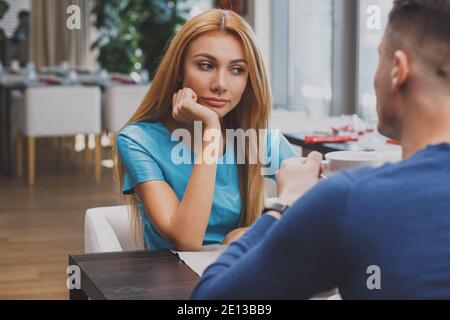 Schöne Frau suchen gelangweilt an ihrem Datum im Restaurant. Attraktive Frau, die unglücklich und deprimiert beim Frühstück mit ihrem Freund. Trennung Stockfoto