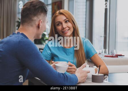 Wunderschöne fröhliche Frau lächelt, genießen Kaffee mit ihrem Freund im lokalen Restaurant. Schönes Paar, das zusammen im Café frühstückte Stockfoto