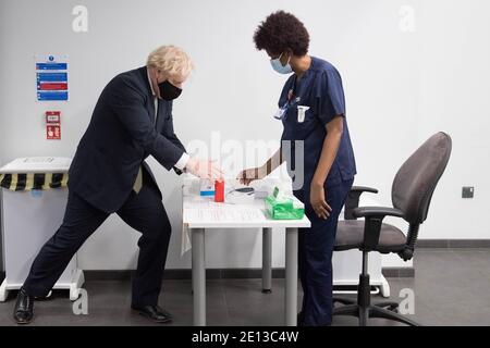 Premierminister Boris Johnson verwendet bei einem Besuch ein Handdesinfektionsmittel, um das Impfprogramm im Chase Farm Hospital im Norden Londons, Teil des Royal Free London NHS Foundation Trust, zu sehen. Der NHS wird sein Impfprogramm mit 530,000 Dosen des neu zugelassenen Oxford/AstraZeneca Covid-19 Impfstoffs, der in ganz Großbritannien eingeführt werden kann, ausweiten. Stockfoto