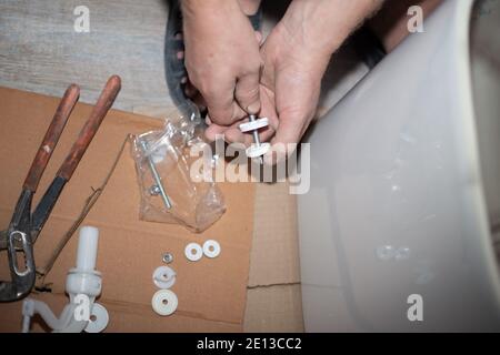 Montage der Toilettenspülung. Renovierung des Hauses. Klempner bei der Arbeit. Stockfoto