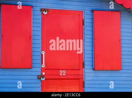 Farbenfrohe Details einer leuchtend roten und blauen Strandhütte auf der Westward Ho Seafront mit Blick auf den Strand und Torridge Mündung. Westward Ho!, Devon, England. Stockfoto