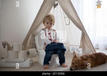 Nettes Kleinkind Kind, Junge, sitzt auf einem Baby-WC Töpfchen, spielt mit Spielzeug Stockfoto