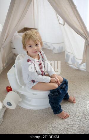 Nettes Kleinkind Kind, Junge, sitzt auf einem Baby-WC Töpfchen, spielt mit Spielzeug Stockfoto