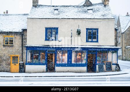 Burford Geschäfte in der High Street im Dezember Schnee. Burford, Cotswolds, Oxfordshire, England Stockfoto