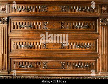 Kommode aus Vintage-Holz mit geschnitzten Details, Messinggriffen und zentralen Schlüssellochen in Nahaufnahme Detail Stockfoto